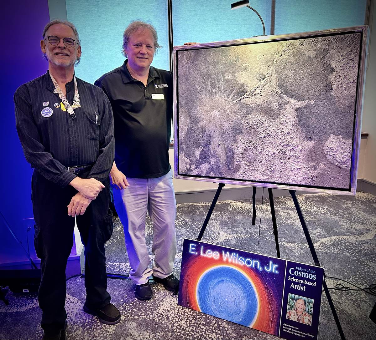 E. Lee Wilson Jr. and another presenter standing beside a large textured science-based artwork.